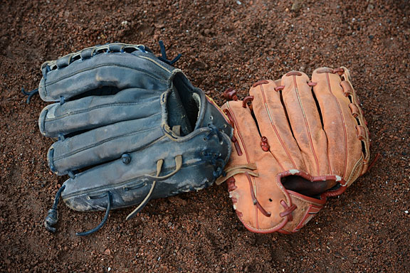 baseball gloves on brown dirt