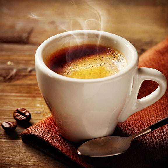 cup of espresso with two roasted coffee beans