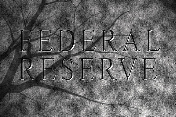 bare tree branches shadow a Federal Reserve sign