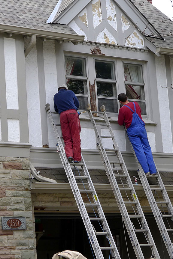 two house painters standing on extension ladders