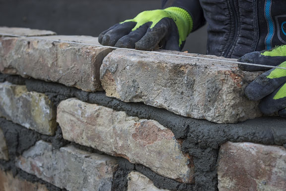 mason building a brick wall