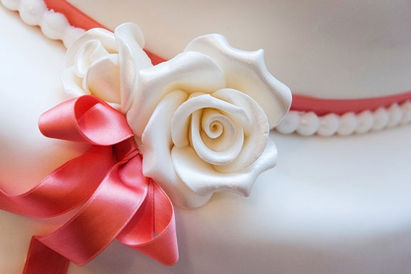white rose and pink ribbon on a wedding cake