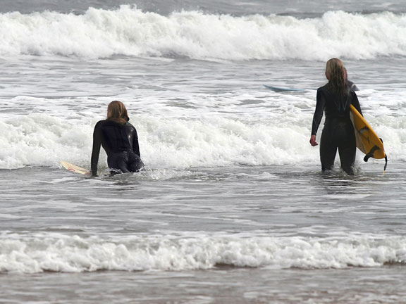 two surfers wearing wet suits